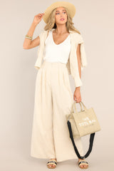Wide leg, natural, linen blend pants paired with a white t-shirt and matching sweater. 