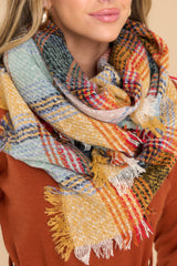Close up view of this scarf that features a plaid pattern throughout with fringe sides.