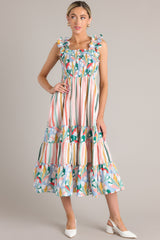 Full front view of this dress that features a square neckline, smocked straps, a fully smocked bust section, functional pockets at the hips, and a flowy skirt.