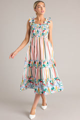 Front view of this dress that features a square neckline, smocked straps, a fully smocked bust section, functional pockets at the hips, and a flowy skirt.