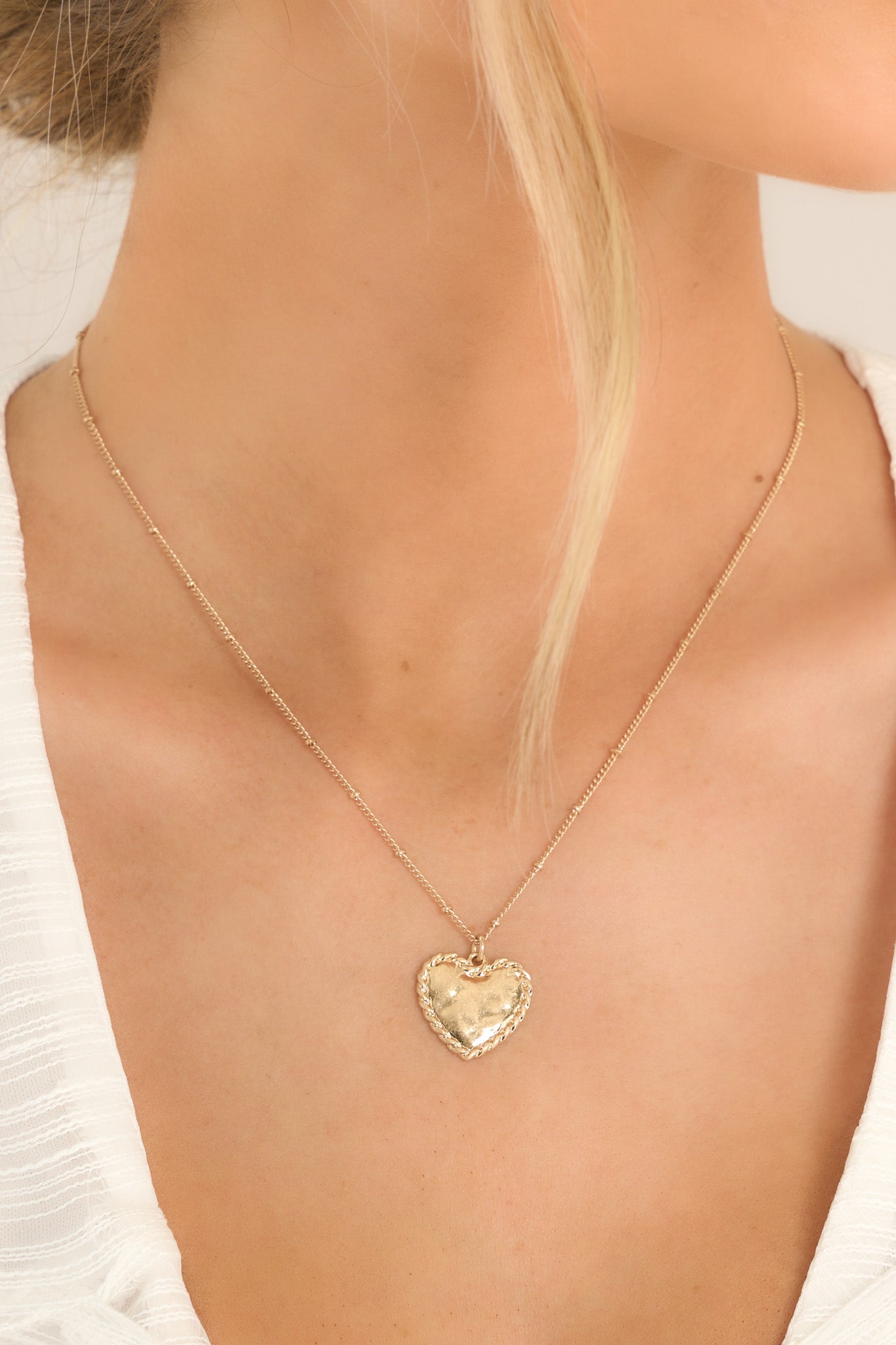 Close up view of this necklace that features gold hardware, a heart shaped pendant, and a lobster clasp closures with a 3