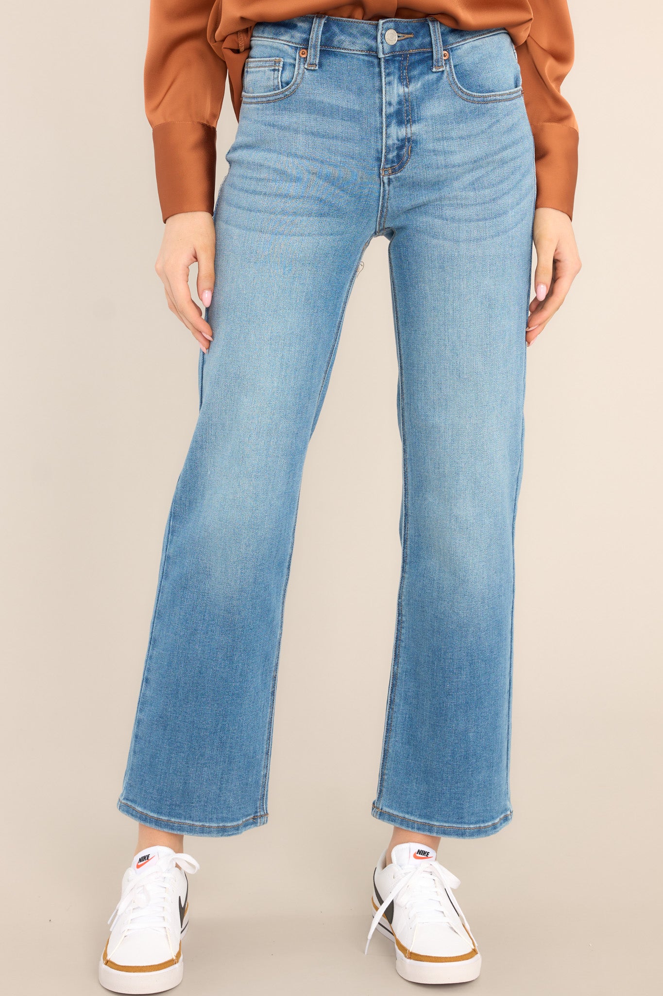 These medium wash jeans feature a high waist design, a zipper and button closure, functional belt loops and pockets, and a straight leg.