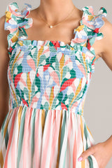 Close up view of this dress that features a square neckline, smocked straps, a fully smocked bust section, functional pockets at the hips, and a flowy skirt.