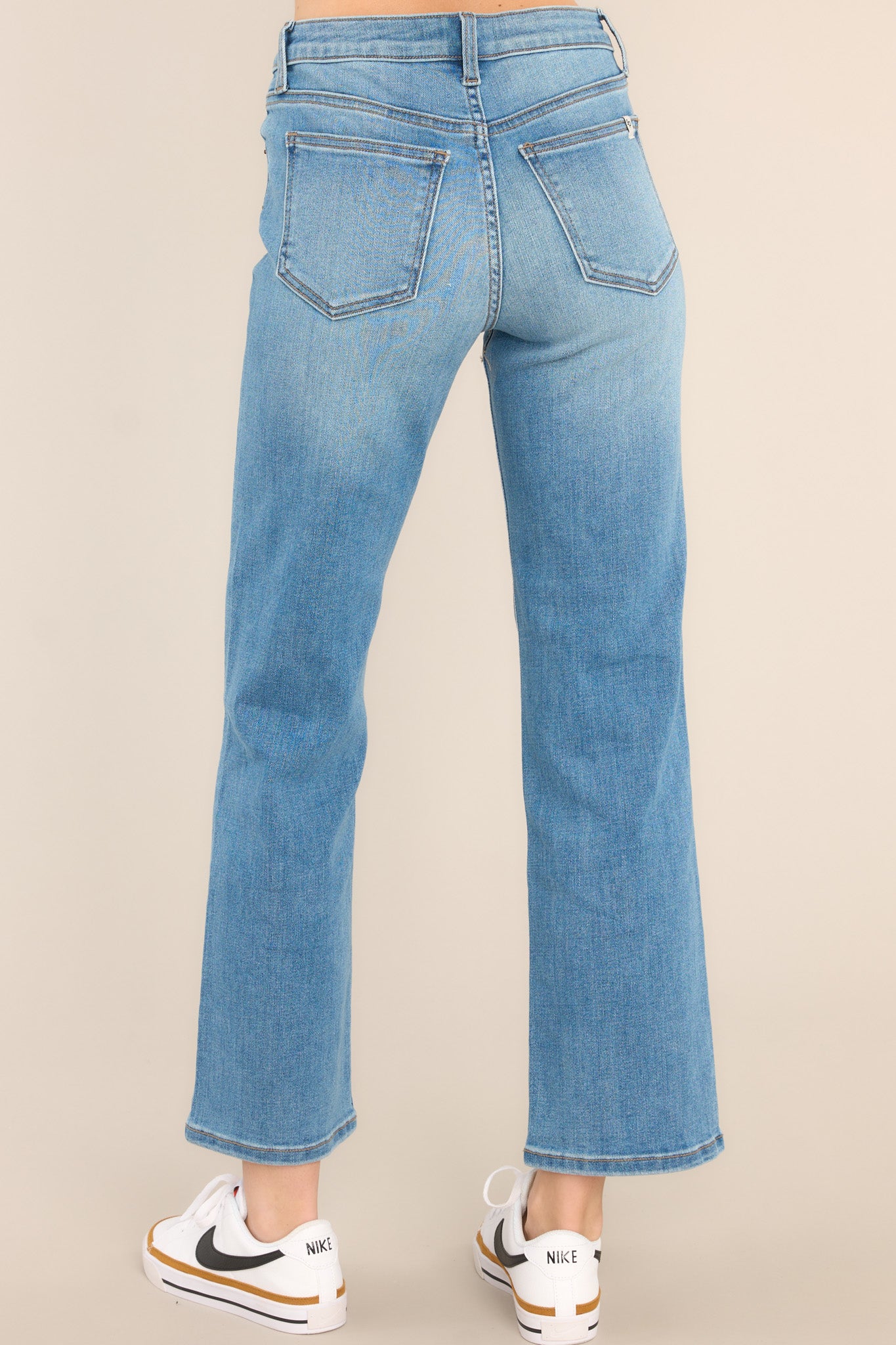 Back view of these jeans that feature a high waist design, a zipper and button closure, functional belt loops and pockets, and a straight leg.