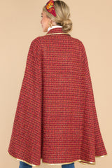 Back view of this cape that features a collar neckline with an adjustable gold bow, gold trim detailing, two functional pockets, and tweed fabric.