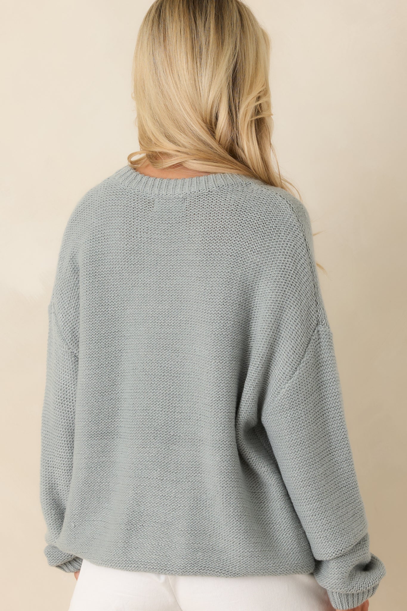 Rear view of the stone blue sweater displaying the smooth knit back, drop shoulder seam, and relaxed fit.