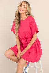 Front view of this dress that features a round neckline, a keyhole cutout at the back of the neck with a button closure, short sleeves, ruffle detailing along the waistline, and functional pockets at the hips.