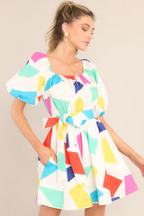 Front view of this dress that features an elastic square neckline, puff sleeves with elastic cuffs, a smocked waistband with an adjustable self-tie, functional waist pockets, and a flowy skirt.