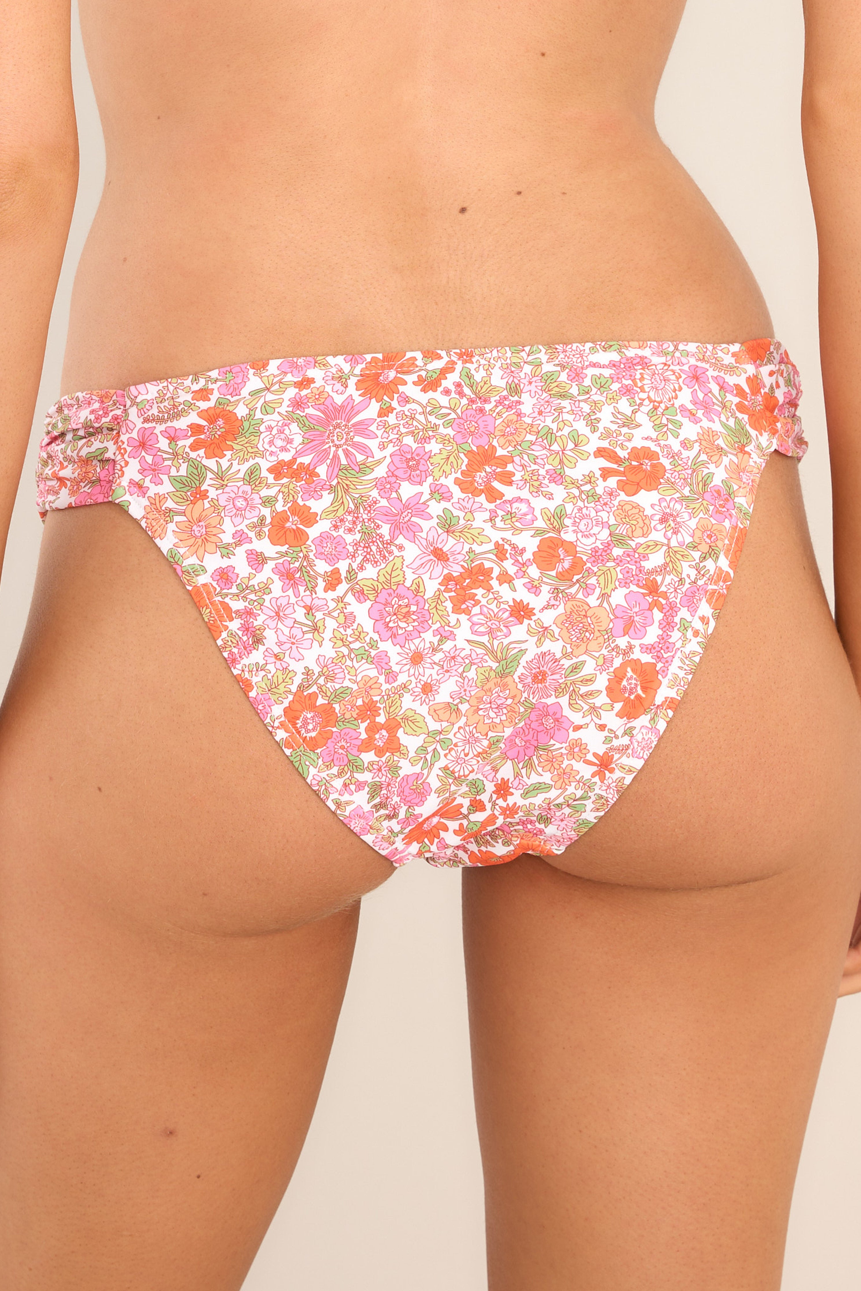 Back view of these bikini bottoms that feature a low rise design, cinched hip detailing, and a slightly cheeky backside.