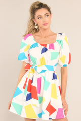 This multi-colored dress features an elastic square neckline, puff sleeves with elastic cuffs, a smocked waistband with an adjustable self-tie, functional waist pockets, and a flowy skirt.