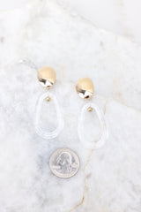 Size comparison of these clear and gold dangle earrings next to a quarter.