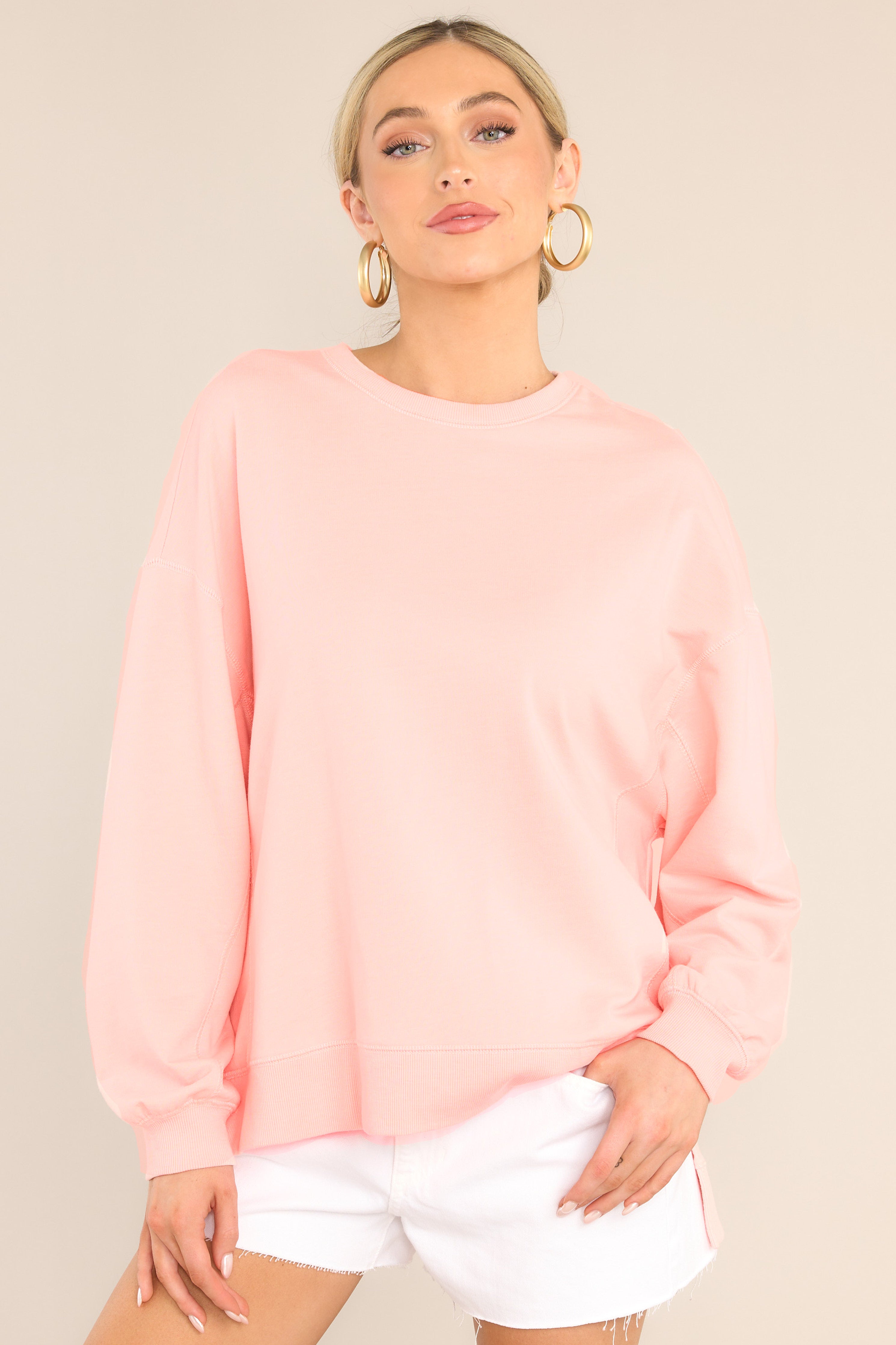 This pink top features a ribbed crew neckline, dropped shoulders, exposed seams, ribbed cuffed sleeves, and a ribbed split high-low hemline.