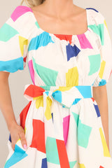 Close up view of this dress that features an elastic square neckline, puff sleeves with elastic cuffs, and a smocked waistband with an adjustable self-tie.