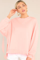 Front view of this top that features a ribbed crew neckline, dropped shoulders, exposed seams, ribbed cuffed sleeves, and a ribbed split high-low hemline.