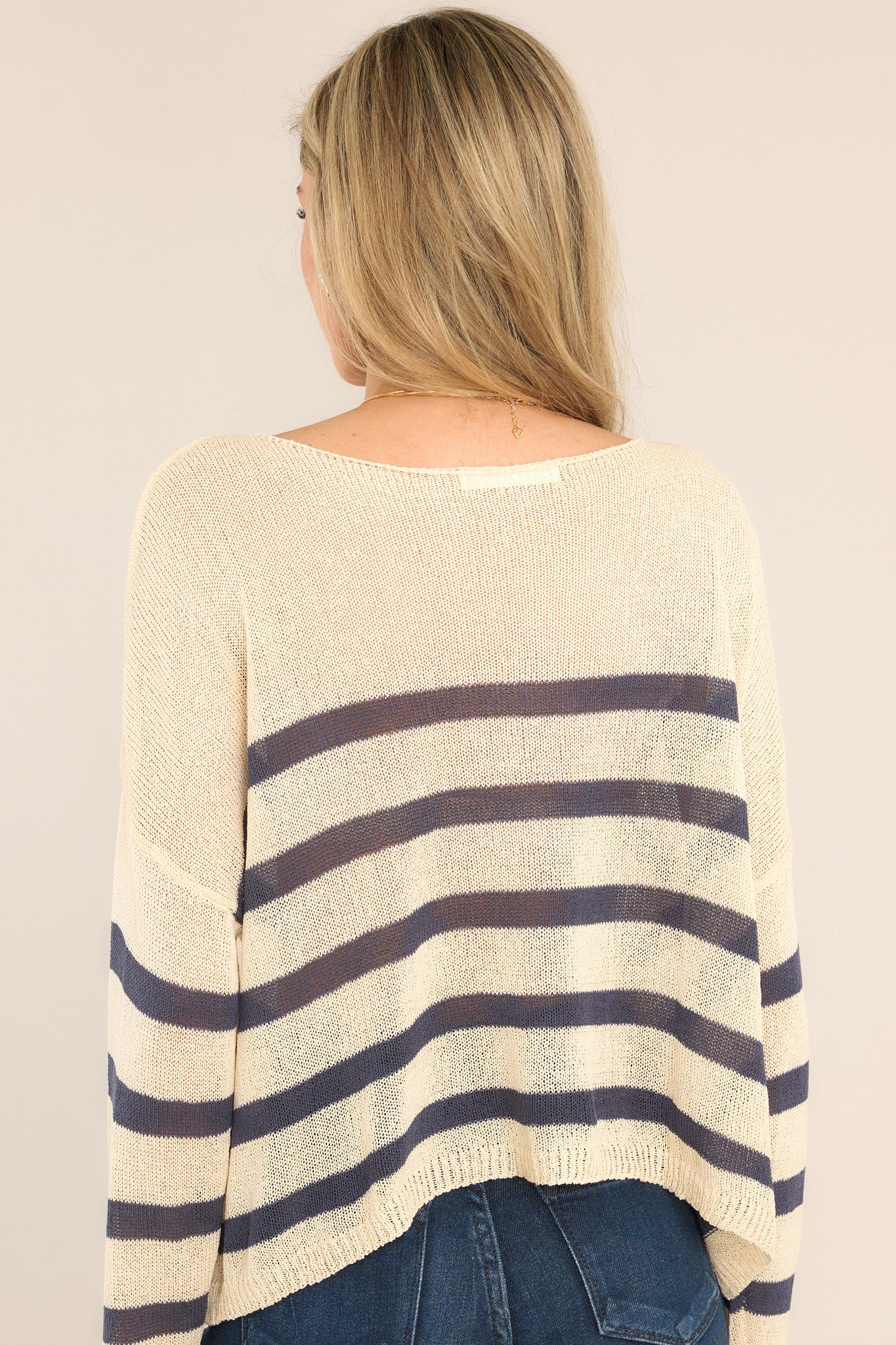 Back view of this sweater that features a wide crew neckline, dropped shoulders, a lightweight knitted material, classic stripes, and long sleeves.