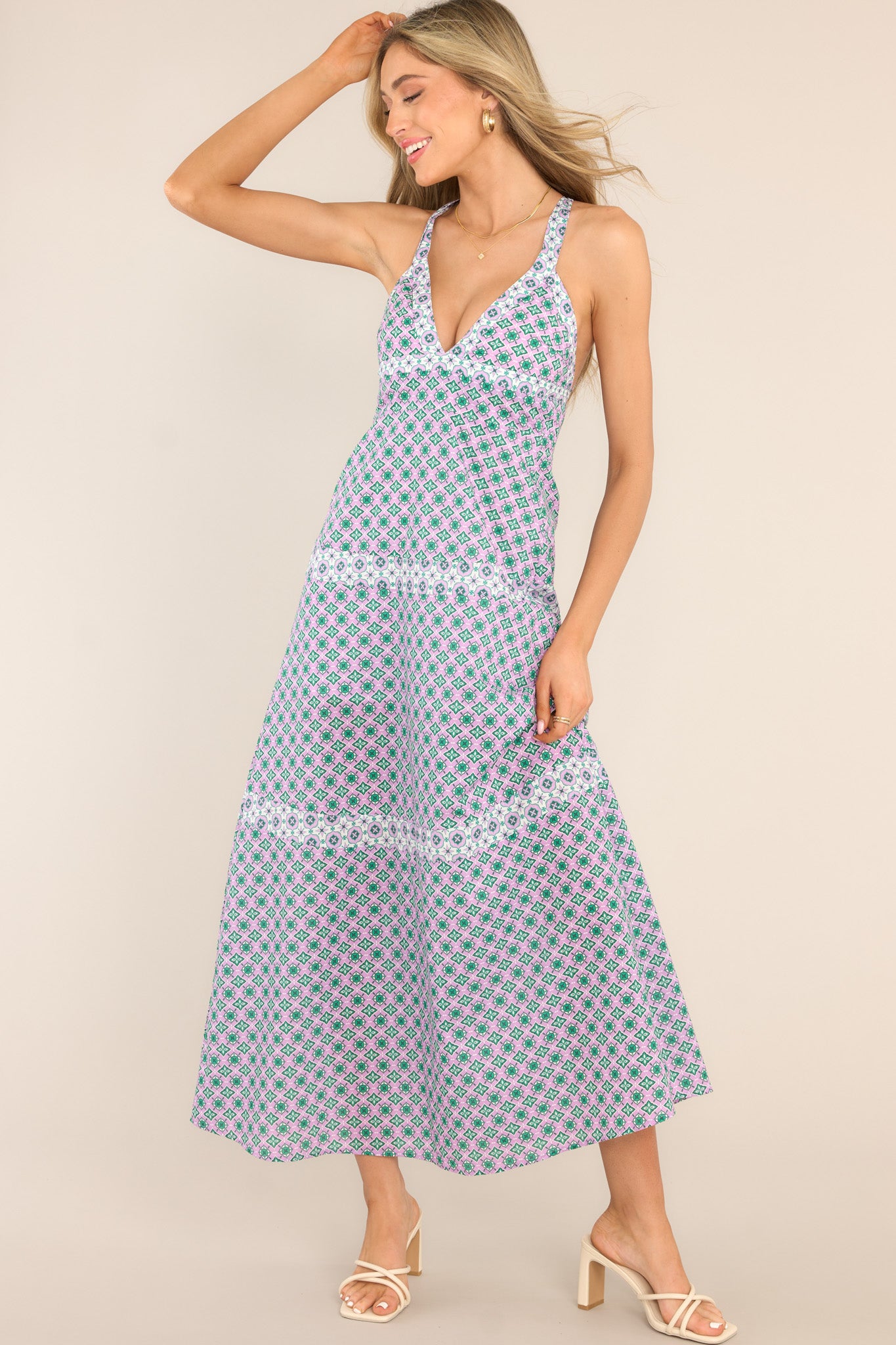 Full body view of this dress that features a deep v-neckline, adjustable straps that cross in the back, a smocked insert in the back, and a tiered design.