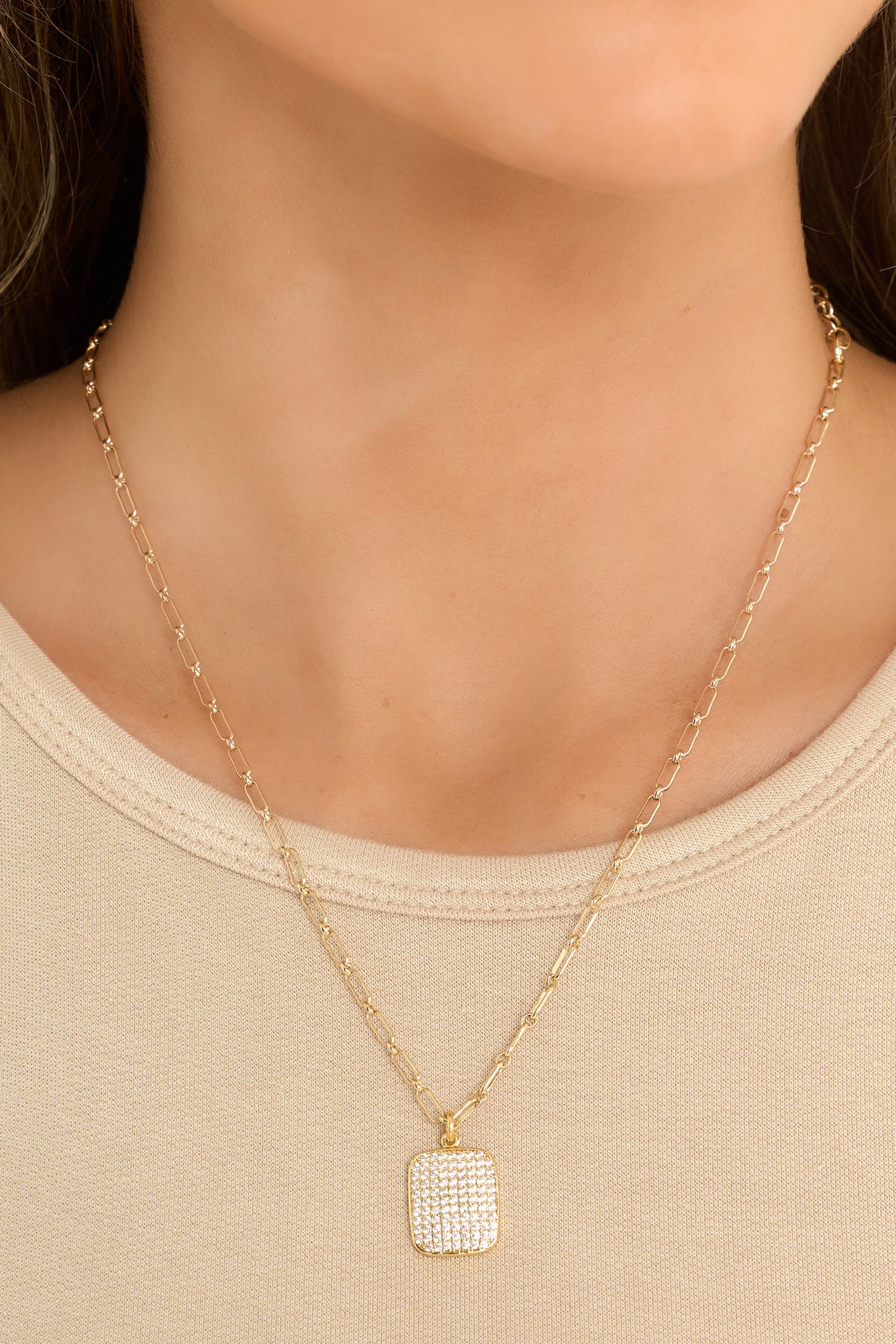 Front view of this gold necklace that features a gold chain, a square rhinestone pendant, and a lobster clasp.