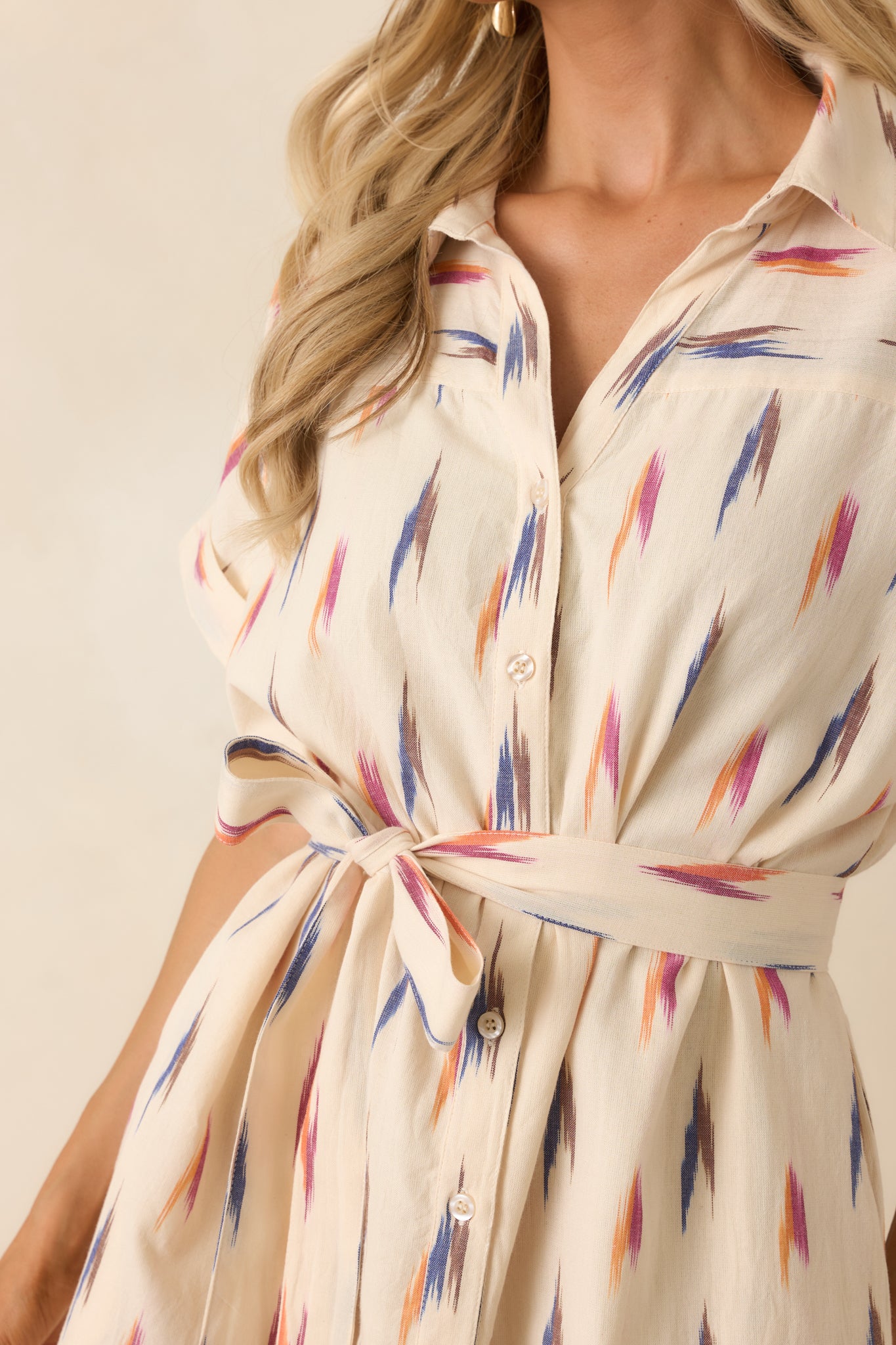 Close-up of the cream cotton fabric highlighting the multicolor brushstroke print, button detailing, and woven texture.