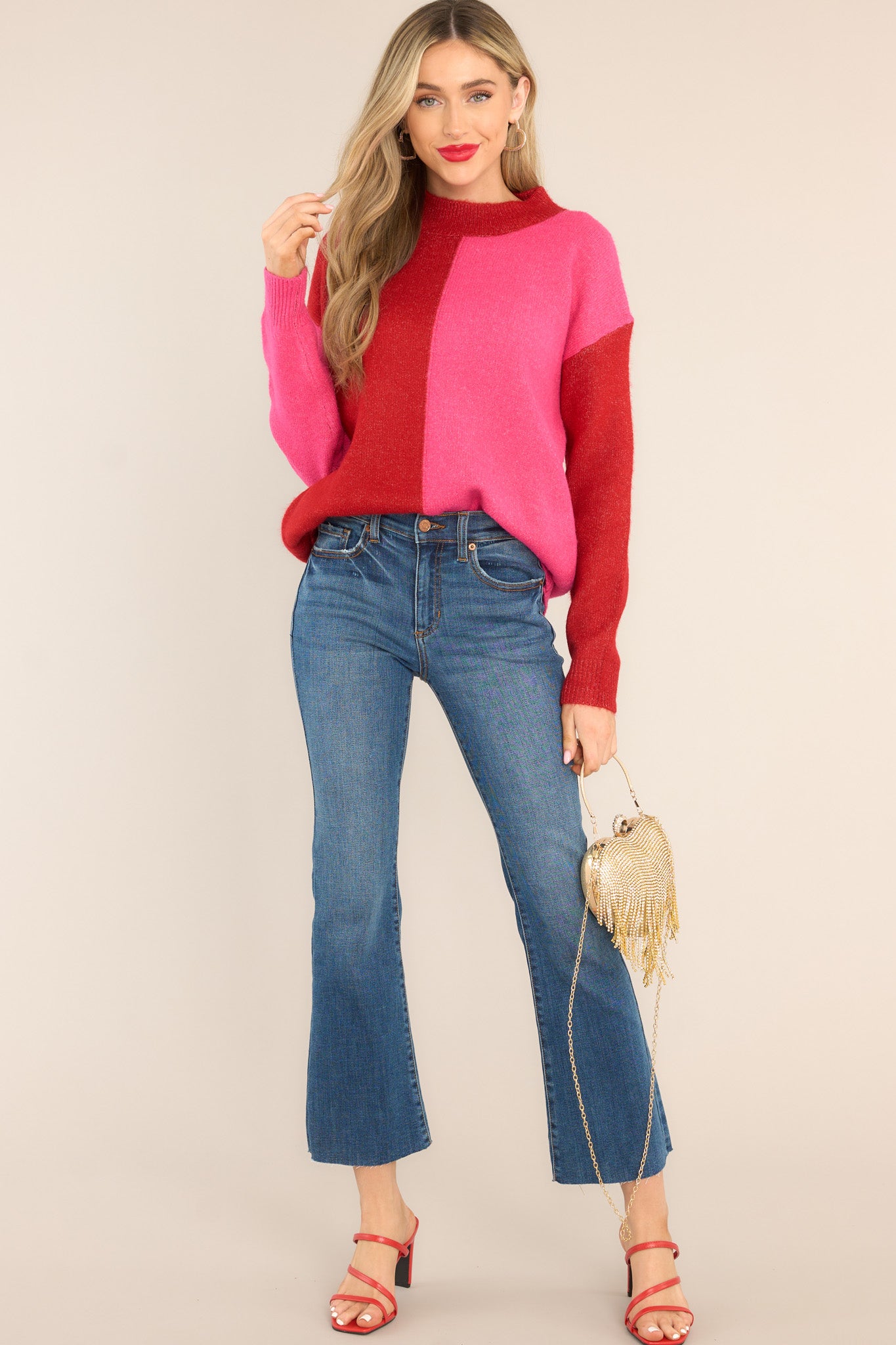 This hot pink and red sweater features a high neckline, a two toned color pattern, and cuffed long sleeves.