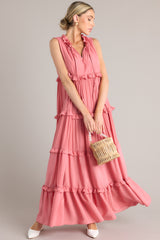 This pink dress features a ruffled v-neckline with a self-tie closure, a sleeveless design, and a flowy skirt with subtle ruffle detailing throughout.