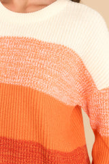 Close up view of this sweater that features a round ribbed neckline, long sleeves, and a fun ombre striped design.