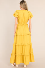Back view of  this dress that features a v-neckline with a self-tie closure, ruffled flutter sleeves, a drawstring waistband, and a long, flowy skirt.