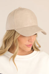 This taupe hat features a faux leather material, and an adjustable velcro strap in the back.