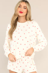 This ivory top features a ribbed crew neckline, an all-over festive print, cuffed long sleeves, and a cuffed hemline. 