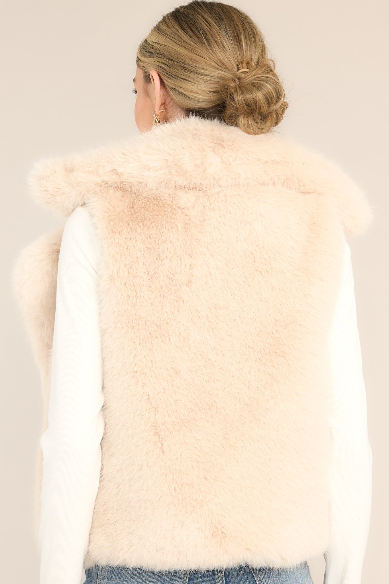 Back view of this vest that features a peak lapel collar, functional pockets, and a faux fur material.