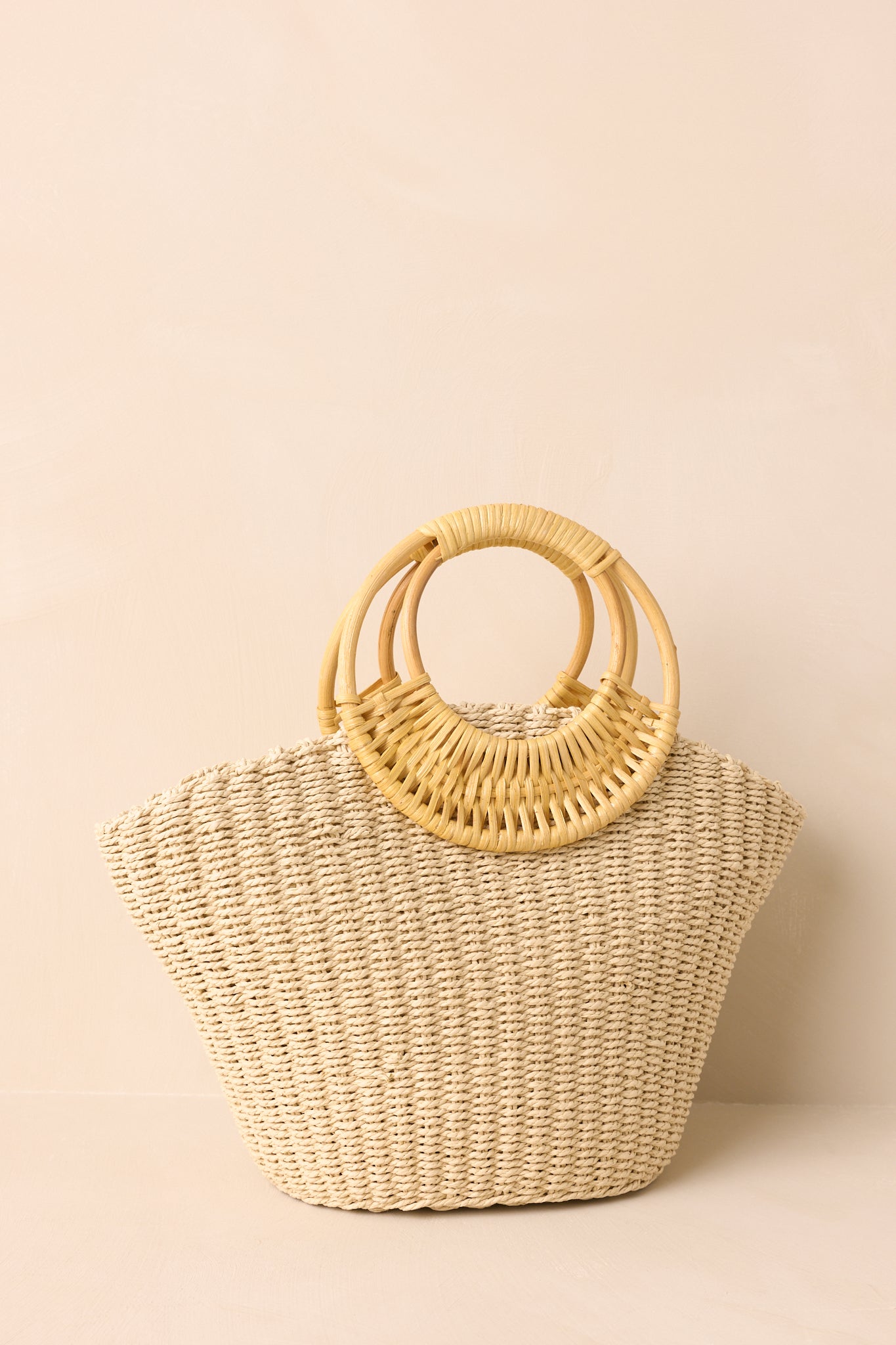 Ivory raffia handbag highlighting bamboo handles and structured shape.