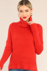 Close-up view of red turtleneck sweater that features dropped shoulders and a cowl-like neckline. 