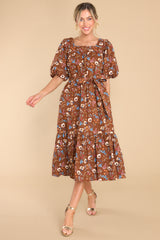 Full view of this dress that features a square neckline, puffed sleeves, a self-tie belt, functional pockets, and a floral pattern.