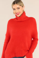 Model shown wearing red turtleneck sweater that features dropped shoulders and a cowl-like neckline. 