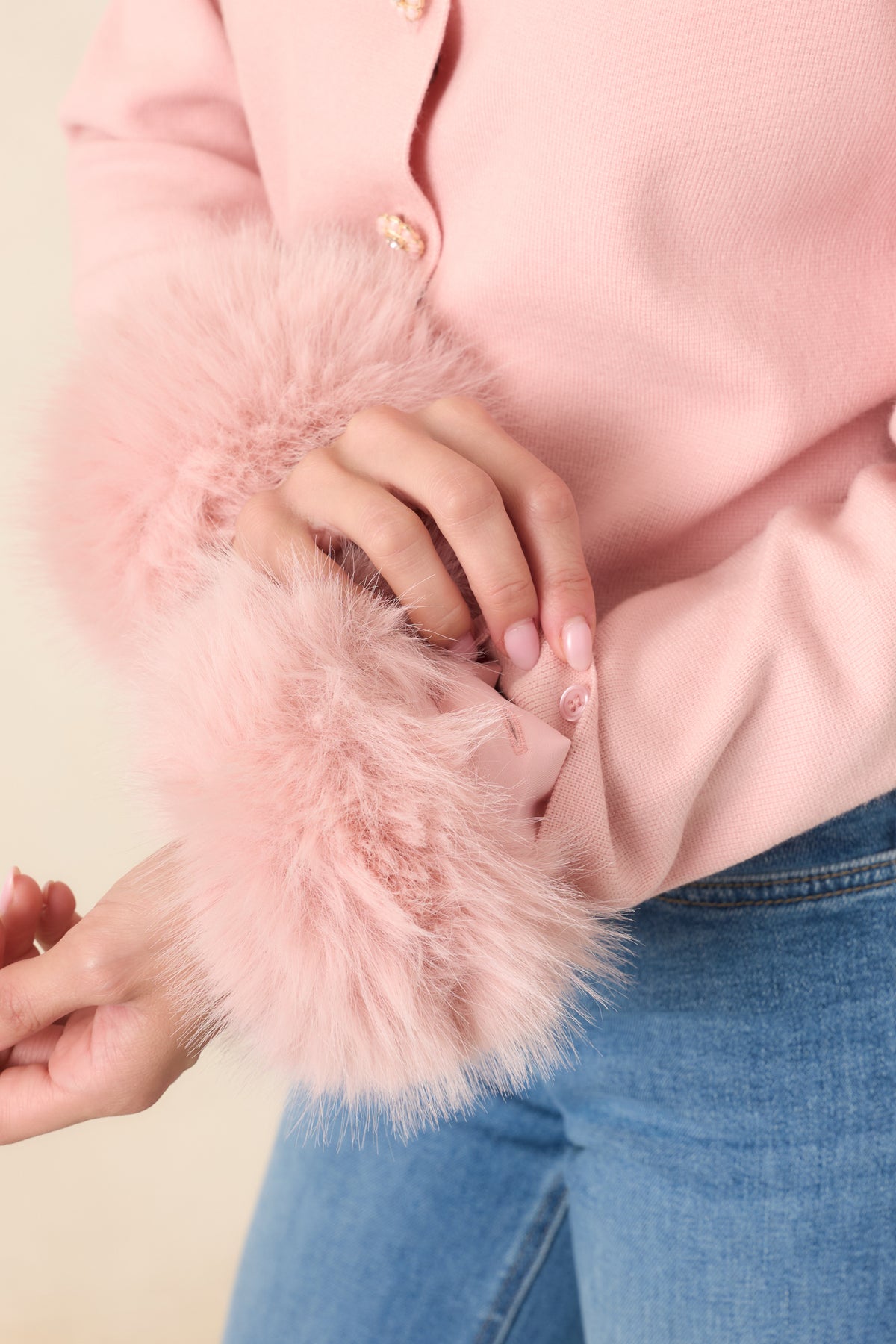 Detail shot of the removable fur cuff on a pink cardigan. 