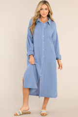 Front view of this dress that features a collared neckline, functional buttons down the front, a front pocket on the left side of the bust, long sleeves with a cuff secured by a functional button, and two slits up the bottom hemline ending just below the knee.