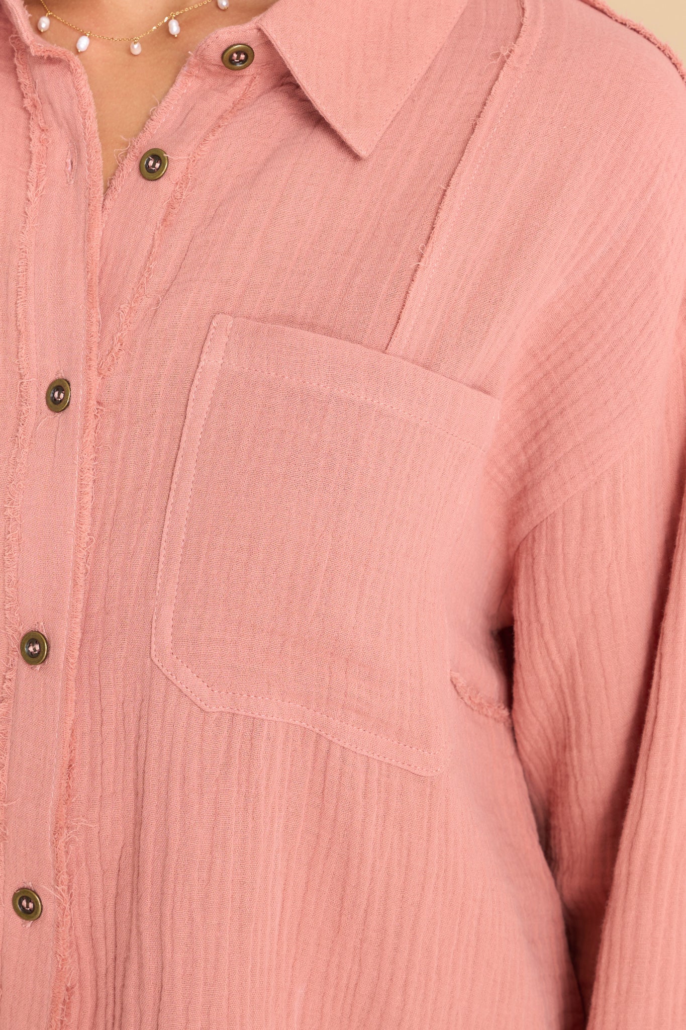 Close up view of this top that features a collared neckline, buttons down the front, and two pockets on the bust.