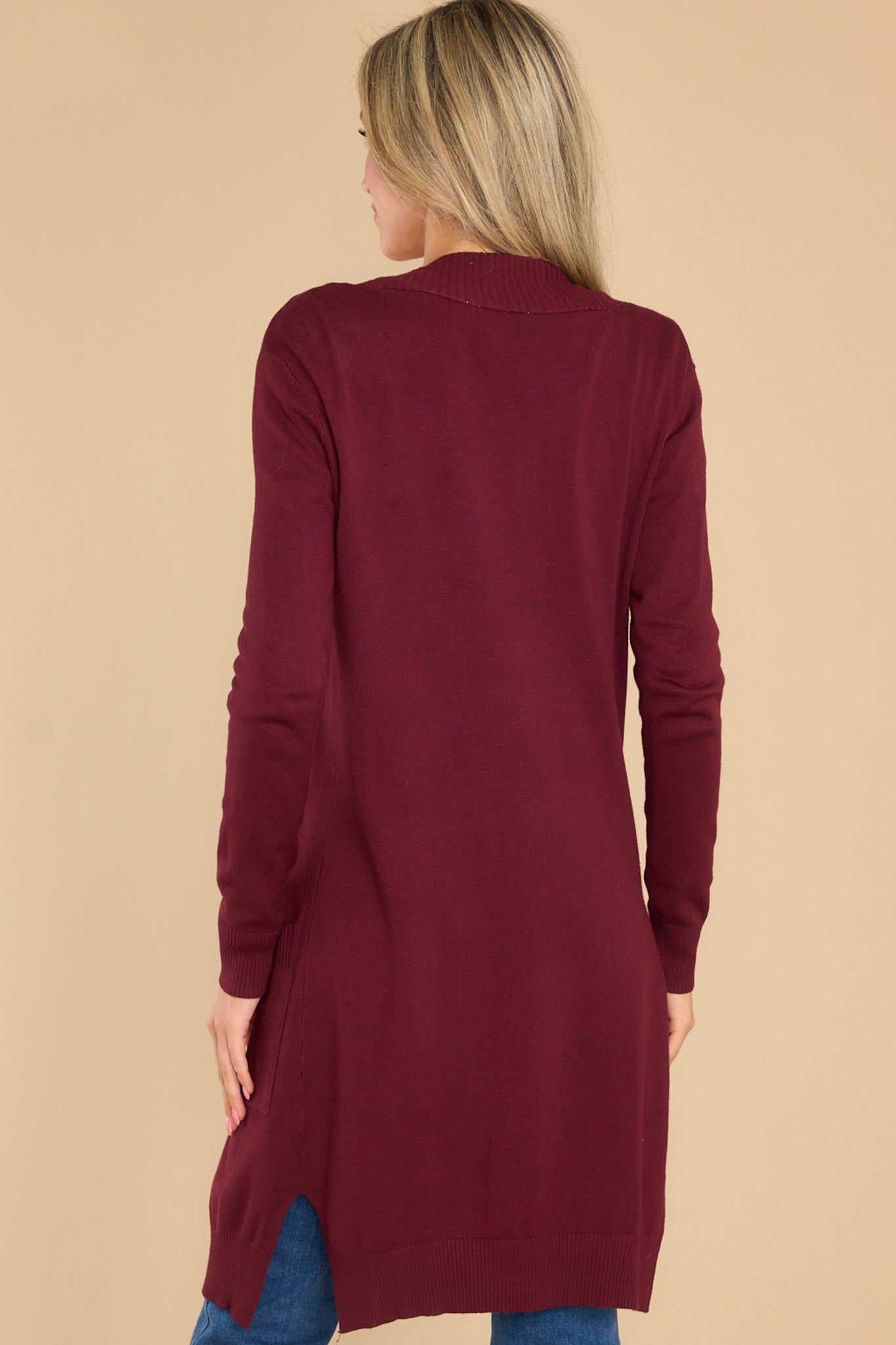 Back view of this cardigan that features an open front accompanied by ribbed details, straight long sleeves, small slits on the sides and functional front pockets.