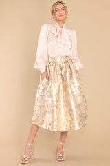 Full body view of  this skirt that features a high waist, raised gold flower details, waist pockets, a hemmed bottom, and a back zipper closure.