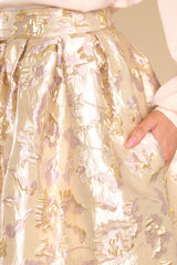 Close up view of  this skirt that features a high waist, raised gold flower details and waist pockets.