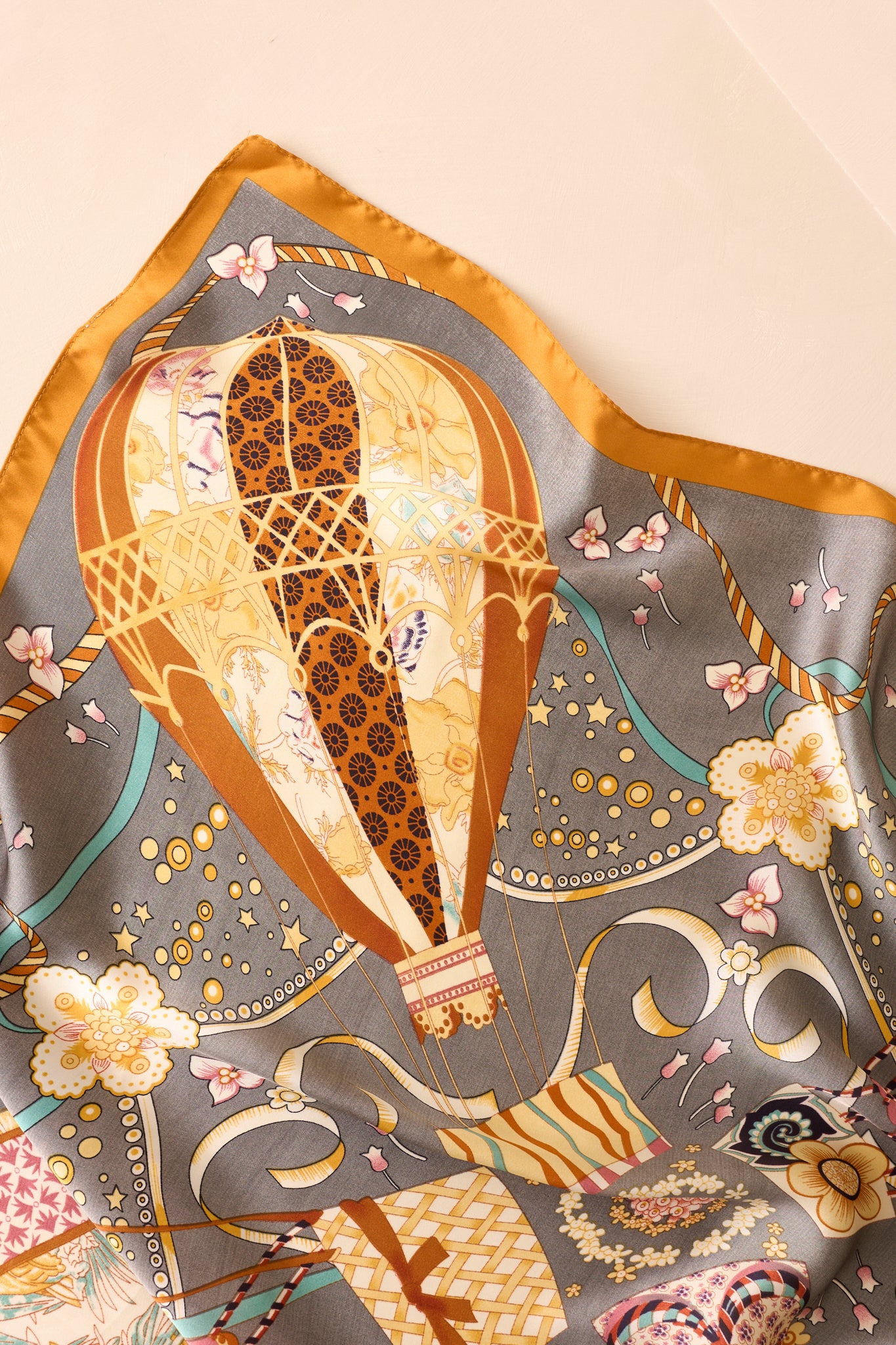 A zoomed-in shot of the scarf's print, showcasing a hot air balloon and its rich hues of gold and yellow.