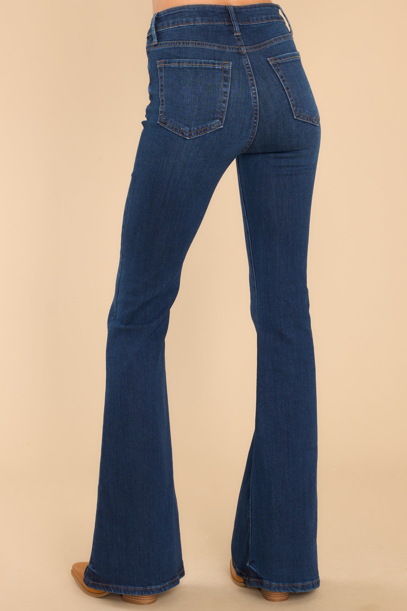 Back view of these jeans that feature a high waist fit, belt loops, zipper and button closure, functional pockets, and a bell bottom flare.