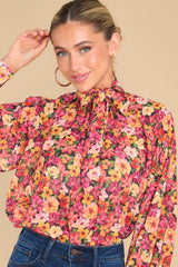 This pink multi print top features a high neck, an adjustable tie back with bow detailing down the back, balloon sleeves, and buttoned cuffs.