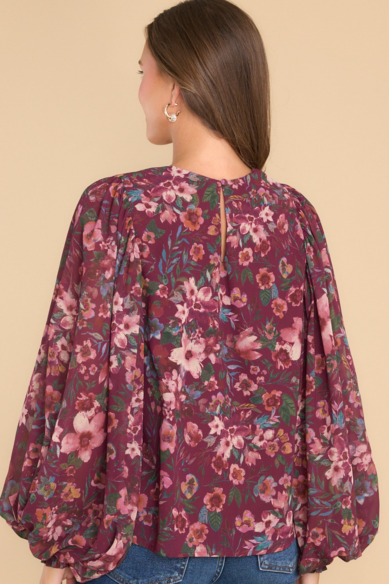 Back view of this top that features a scoop neckline, flowy balloon sleeves with elastic around the cuff, key hole back with a button closure, and a relaxed fit.