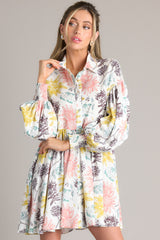 Front view of this dress that features a collared neckline, functional buttons down the front, long balloon sleeves with smocked cuffs, and a flowy, relaxed fit throughout.