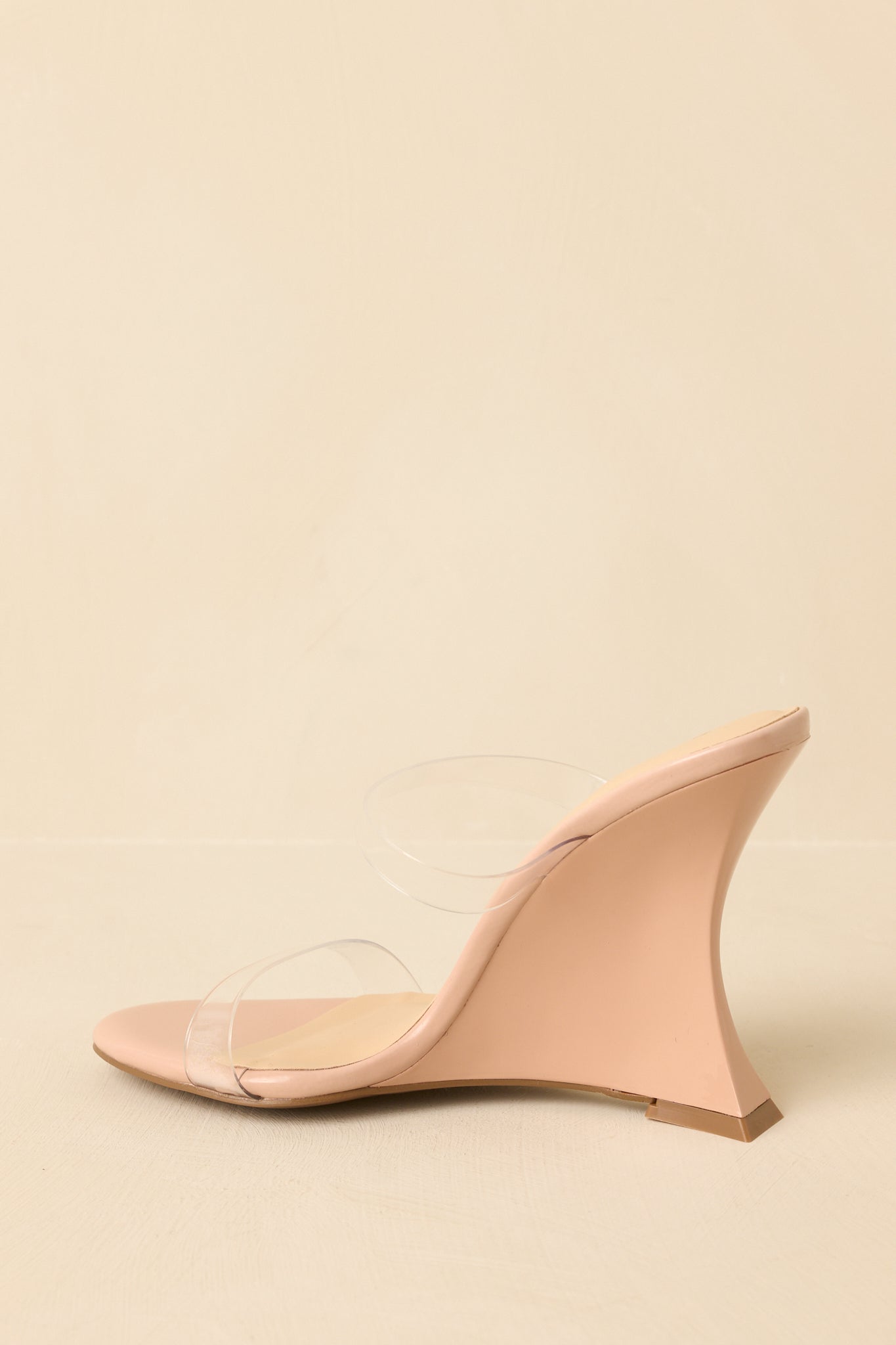 Beige wedge heels angled to emphasize the sleek silhouette and structured wedge shape.