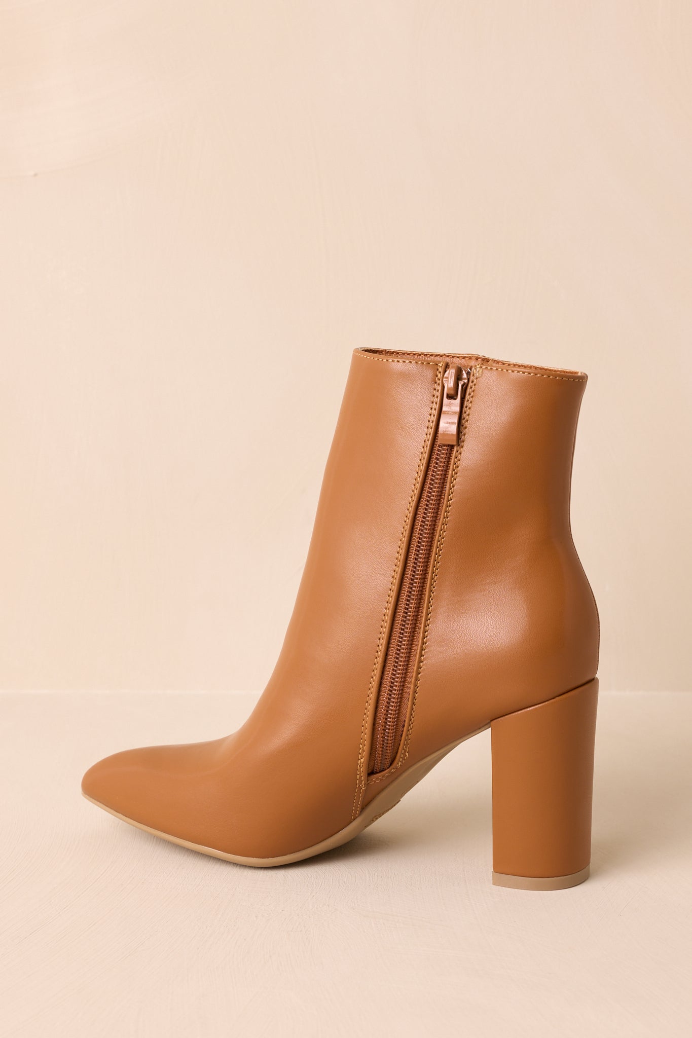 An angled back view of the ankle boots showcasing the caramel zipper and block heel. 