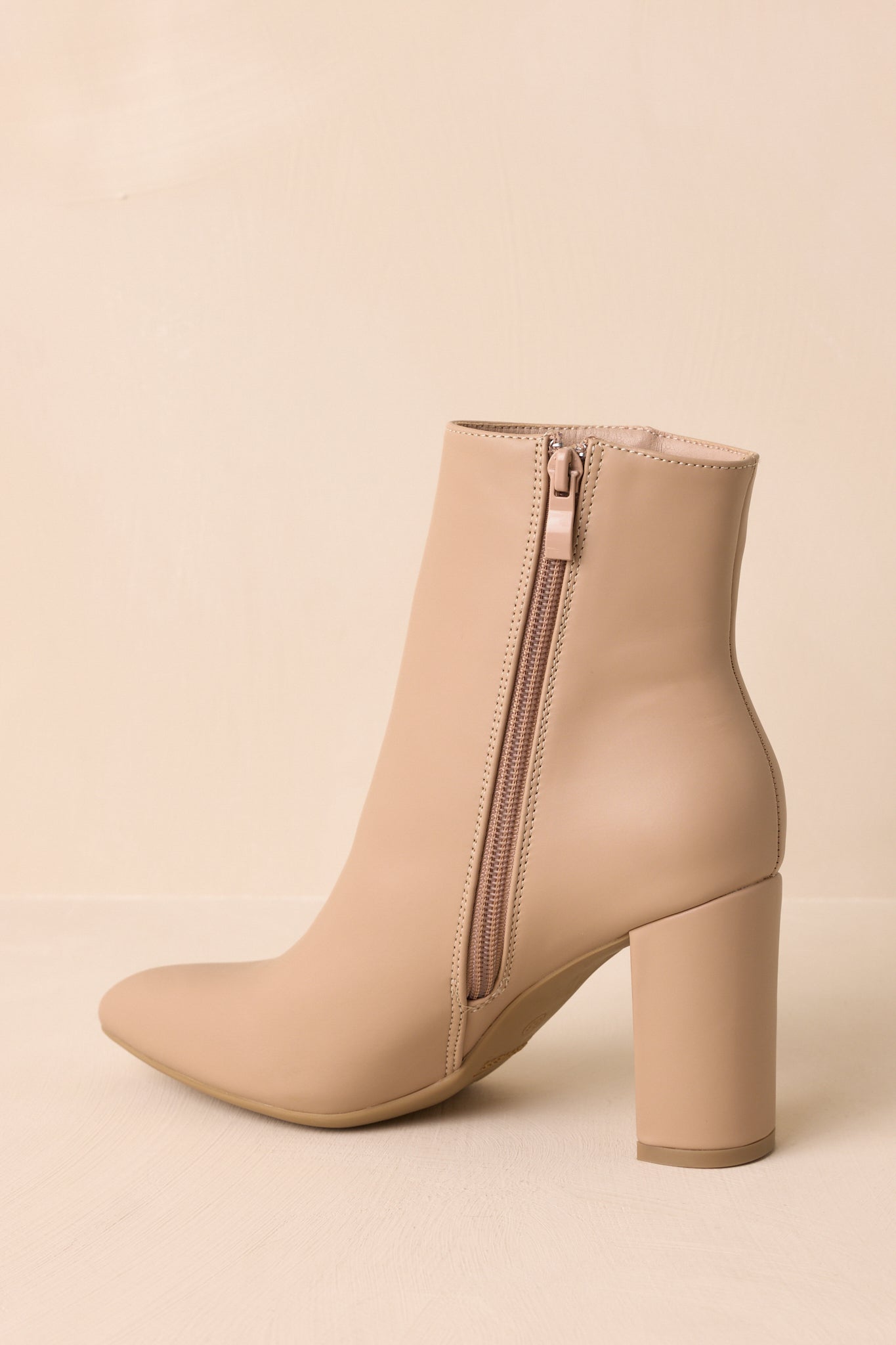 Beige ankle boots turned slightly to the side, showing the zipper closure and block heel shape.