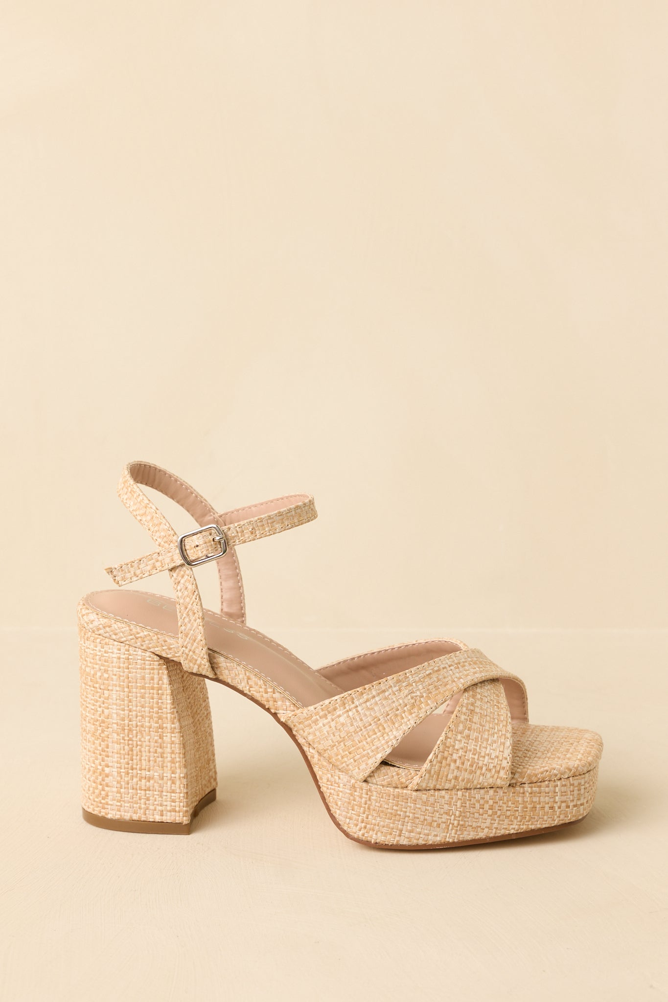 Natural raffia sandals displayed from the side to show the full block heel and cross strap design.