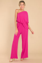 Full body view of  this jumpsuit that features an off the shoulder neckline that goes over the left shoulder with a large dolman sleeve.
