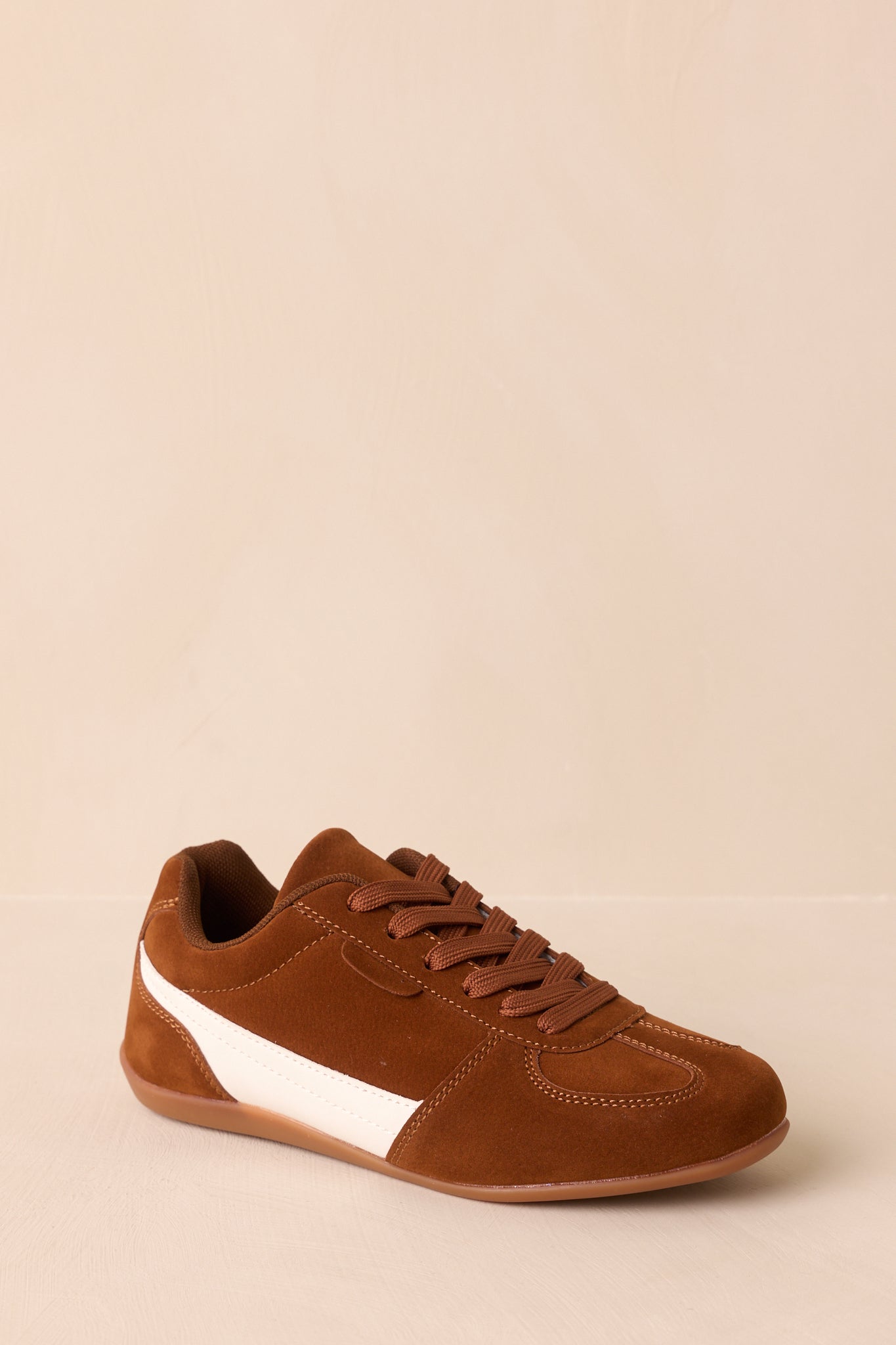 A three-quarter view showing the contrast of brown suede material with white faux leather accents.